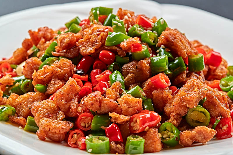 白色瓷盘装的川香口味鲜椒爆鸡丁图片