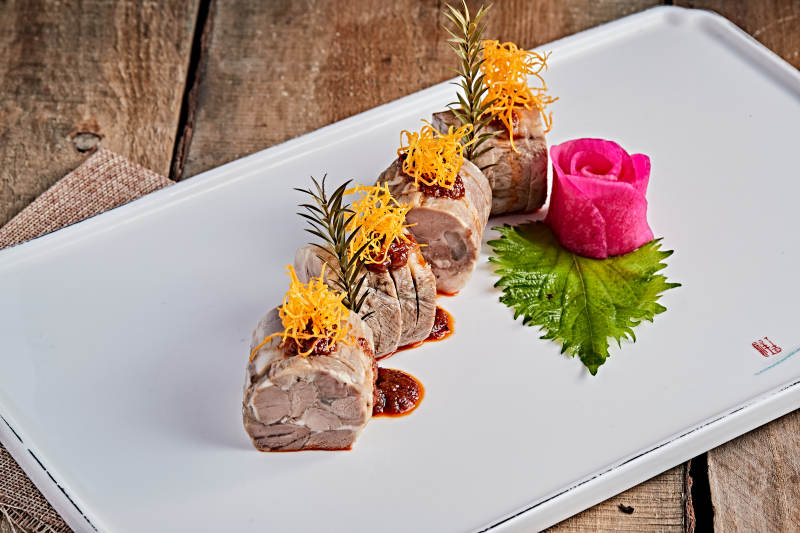 白色瓷盘装的精美凉菜肘花切片图片