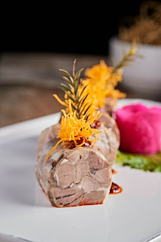 白色瓷盘装的精美凉菜肘花切片图片