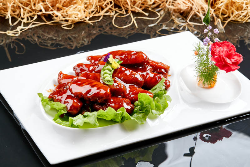 白色瓷盘装的蜜豆酱鸡翅中图片