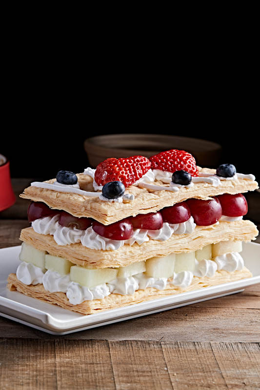 白色瓷盘装的水果戚风奶油拿破仑蛋糕图片