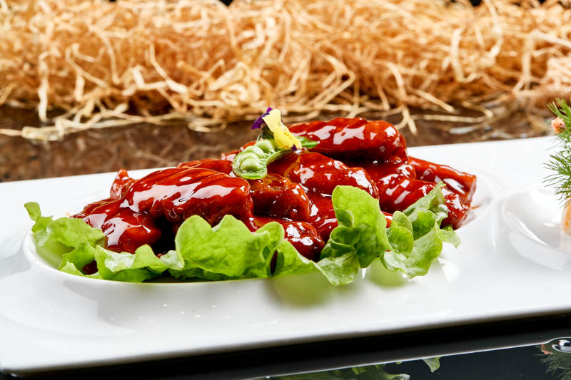 白色瓷盘装的蜜豆酱鸡翅中图片