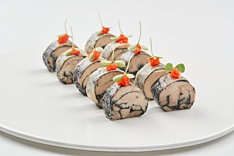 白色瓷盘装的压海苔金枪鱼卷切片图片