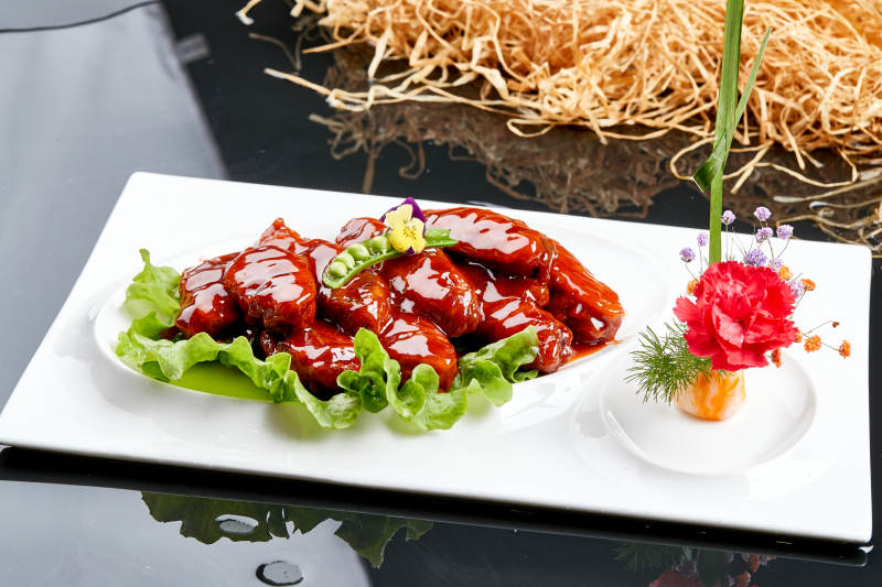 白色瓷盘装的蜜豆酱鸡翅中图片