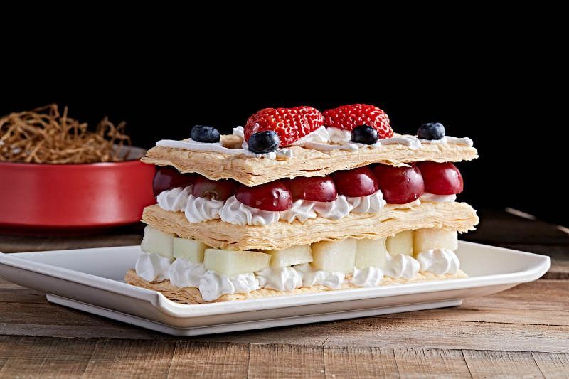 白色瓷盘装的水果戚风奶油拿破仑蛋糕图片