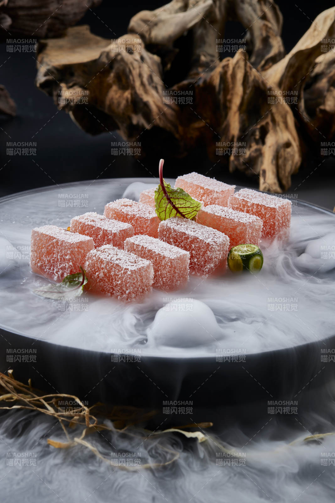干冰缭绕的黑瓷餐具摆放的番茄糖霜江米糕图片