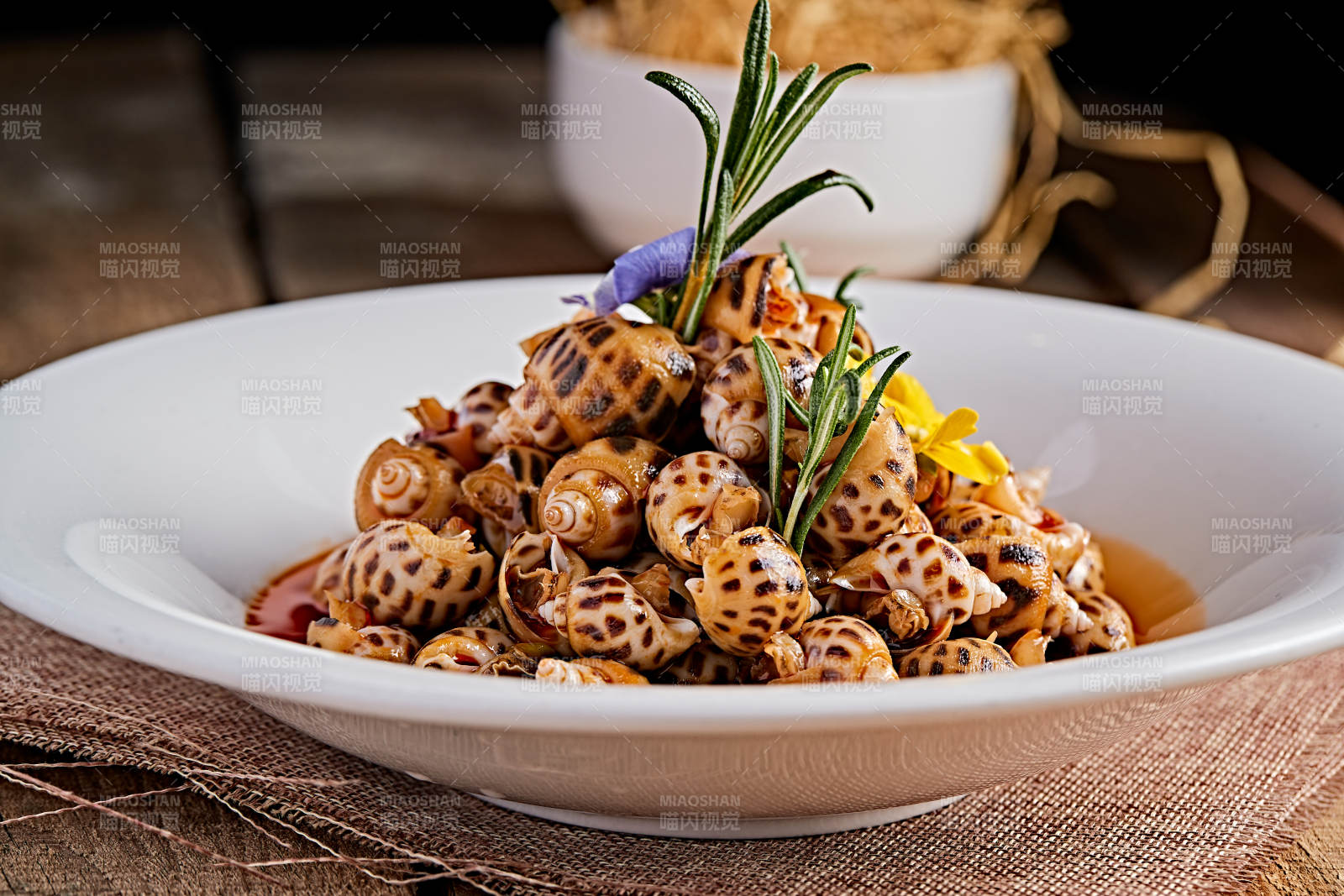 白色瓷盘装的红油腌渍小花螺图片