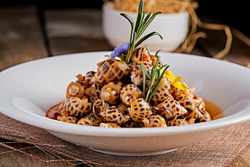 白色瓷盘装的红油腌渍小花螺图片