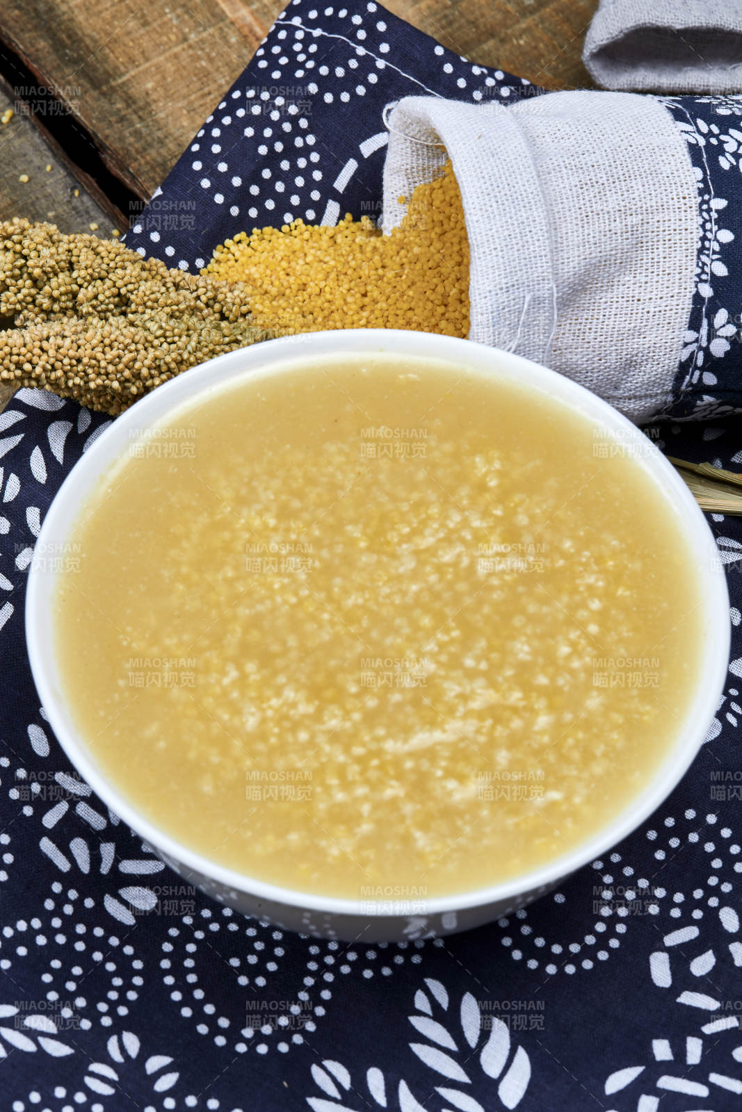 手持木勺㧟起的美味香浓小米粥图片