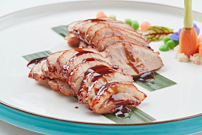 白色瓷盘装的烟熏鸭胸肉切片图片