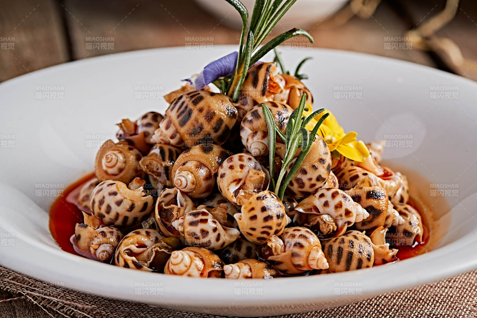 白色瓷盘装的红油腌渍小花螺图片