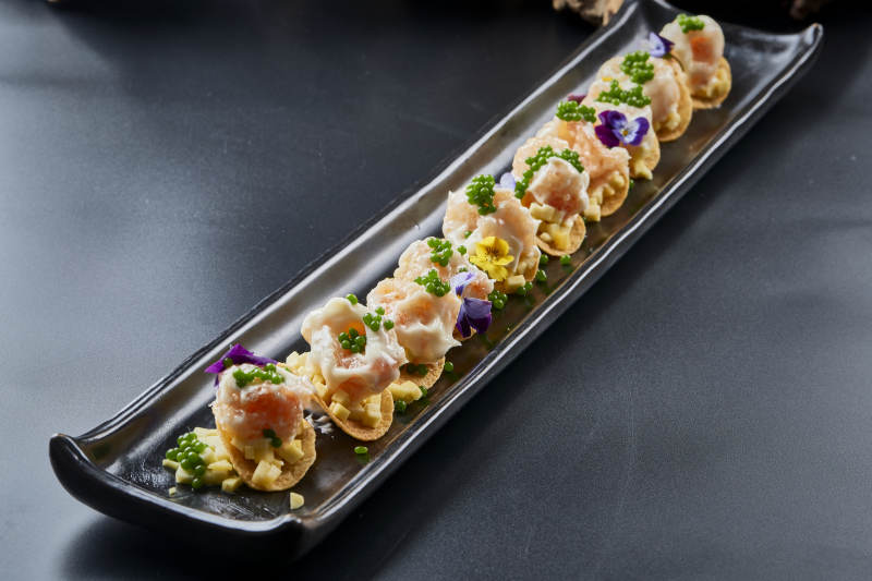 黑色长瓷盘装的青鱼子奶香芝士薯片焗虾仁图片