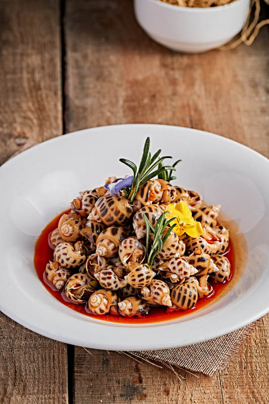 白色瓷盘装的红油腌渍小花螺图片