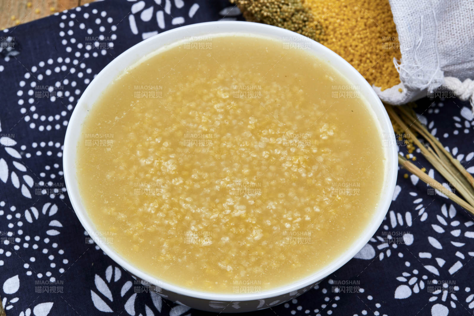 手持木勺㧟起的美味香浓小米粥图片