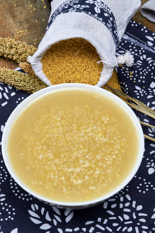 手持木勺㧟起的美味香浓小米粥图片