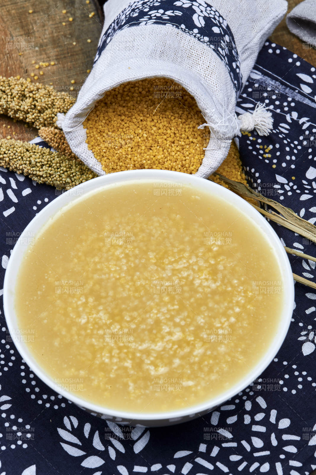 手持木勺㧟起的美味香浓小米粥图片