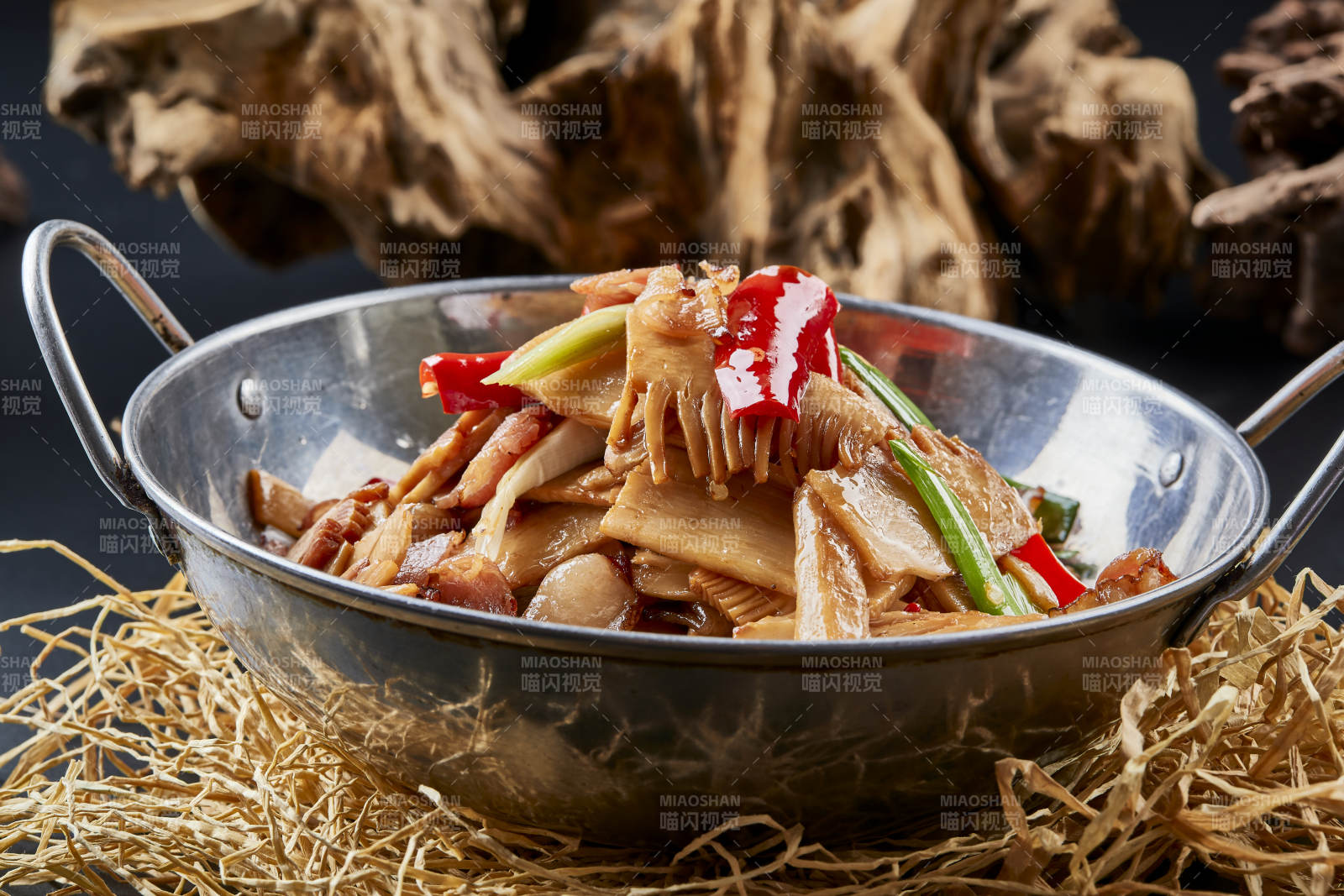 黑色背景上的锅仔香辣腊肉煲鲜笋图片