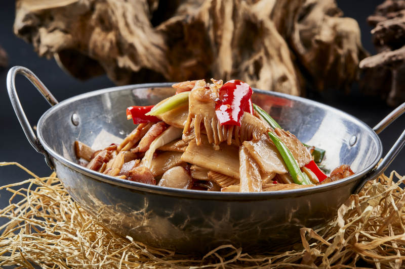 黑色背景上的锅仔香辣腊肉煲鲜笋图片