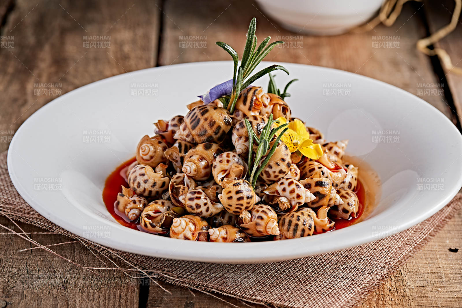 白色瓷盘装的红油腌渍小花螺图片