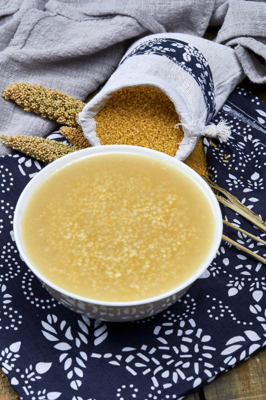 手持木勺㧟起的美味香浓小米粥图片