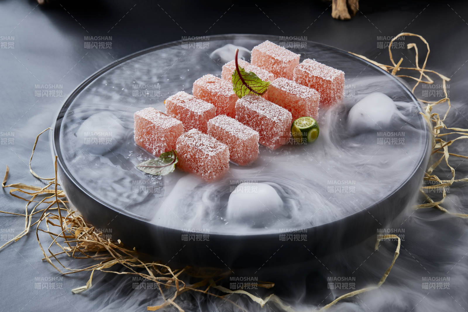 干冰缭绕的黑瓷餐具摆放的番茄糖霜江米糕图片