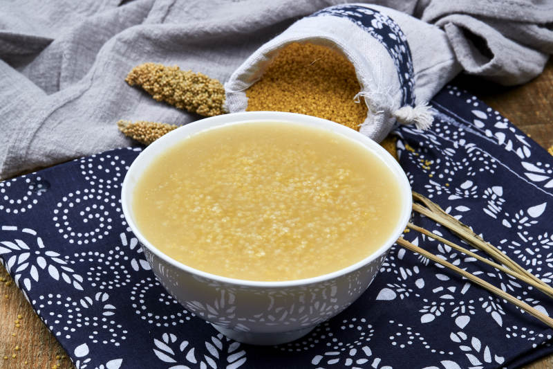 手持木勺㧟起的美味香浓小米粥图片