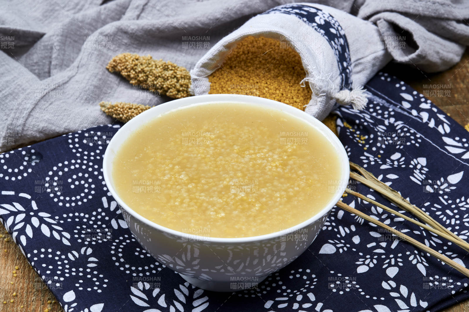 手持木勺㧟起的美味香浓小米粥图片