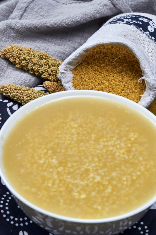 手持木勺㧟起的美味香浓小米粥图片