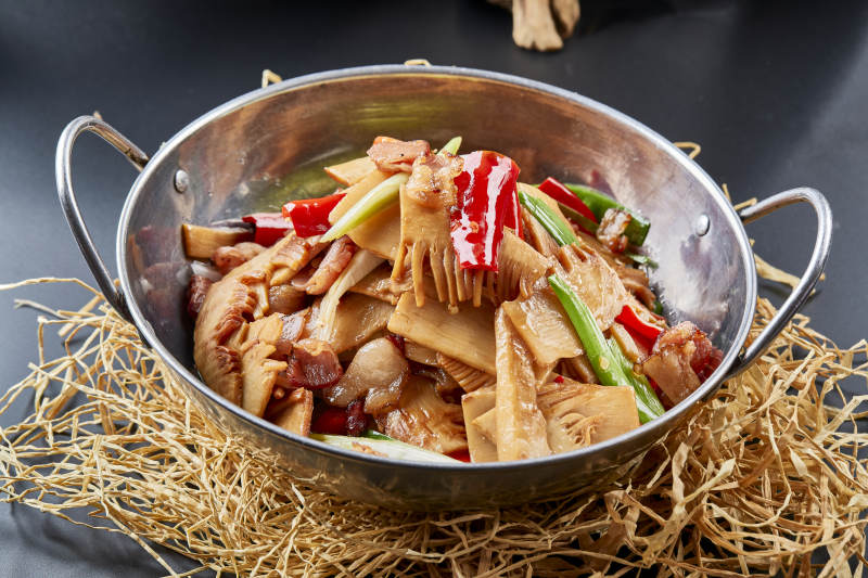 黑色背景上的锅仔香辣腊肉煲鲜笋图片