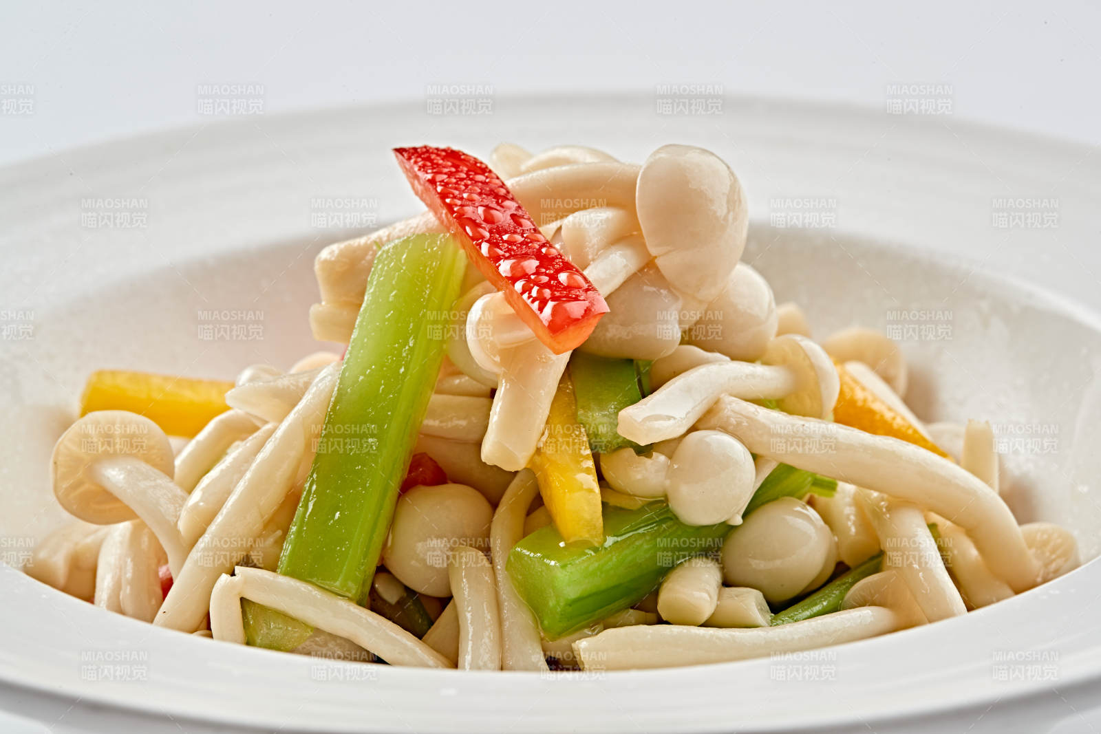 白色瓷盘装的西芹彩椒小炒白玉菇图片