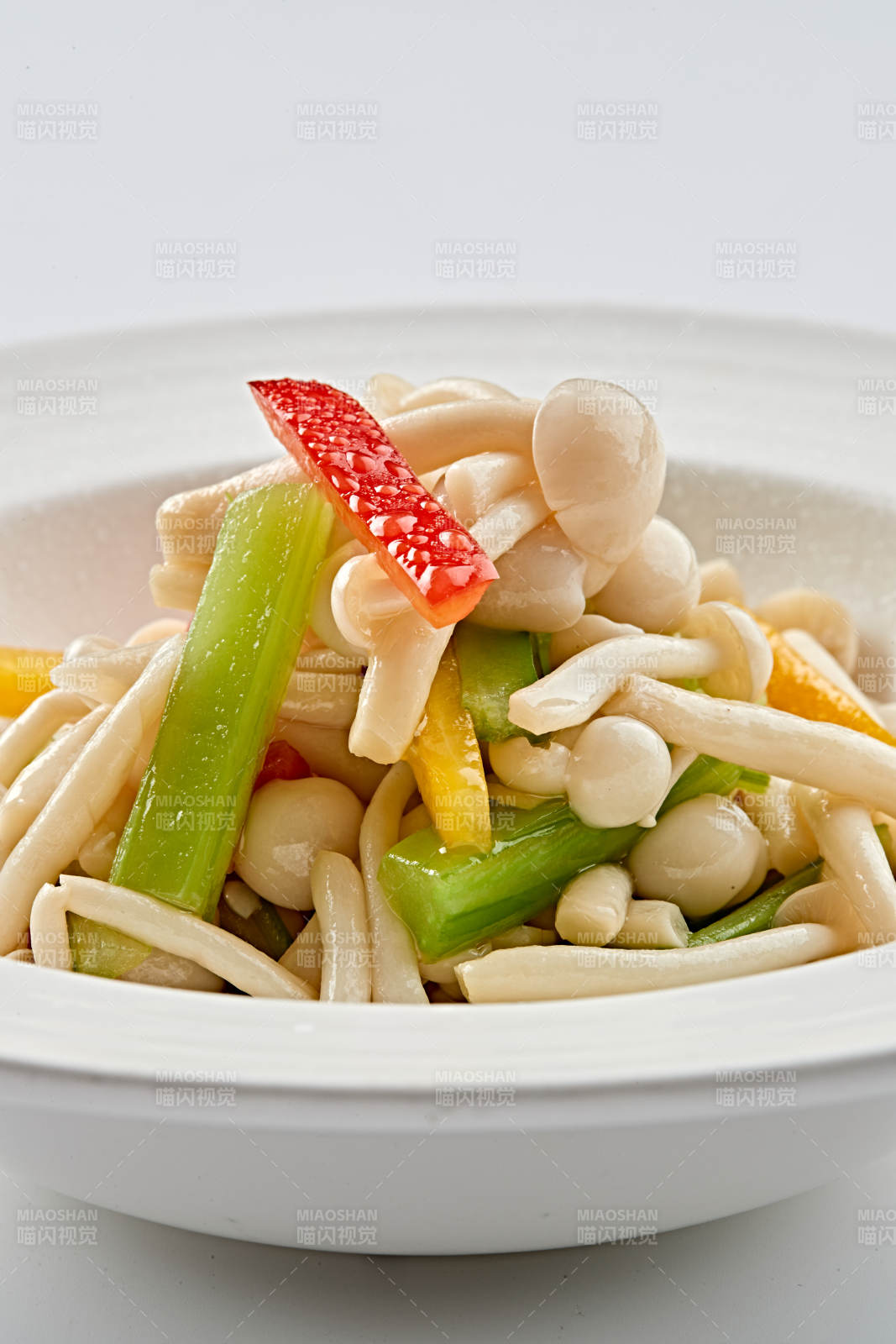 白色瓷盘装的西芹彩椒小炒白玉菇图片