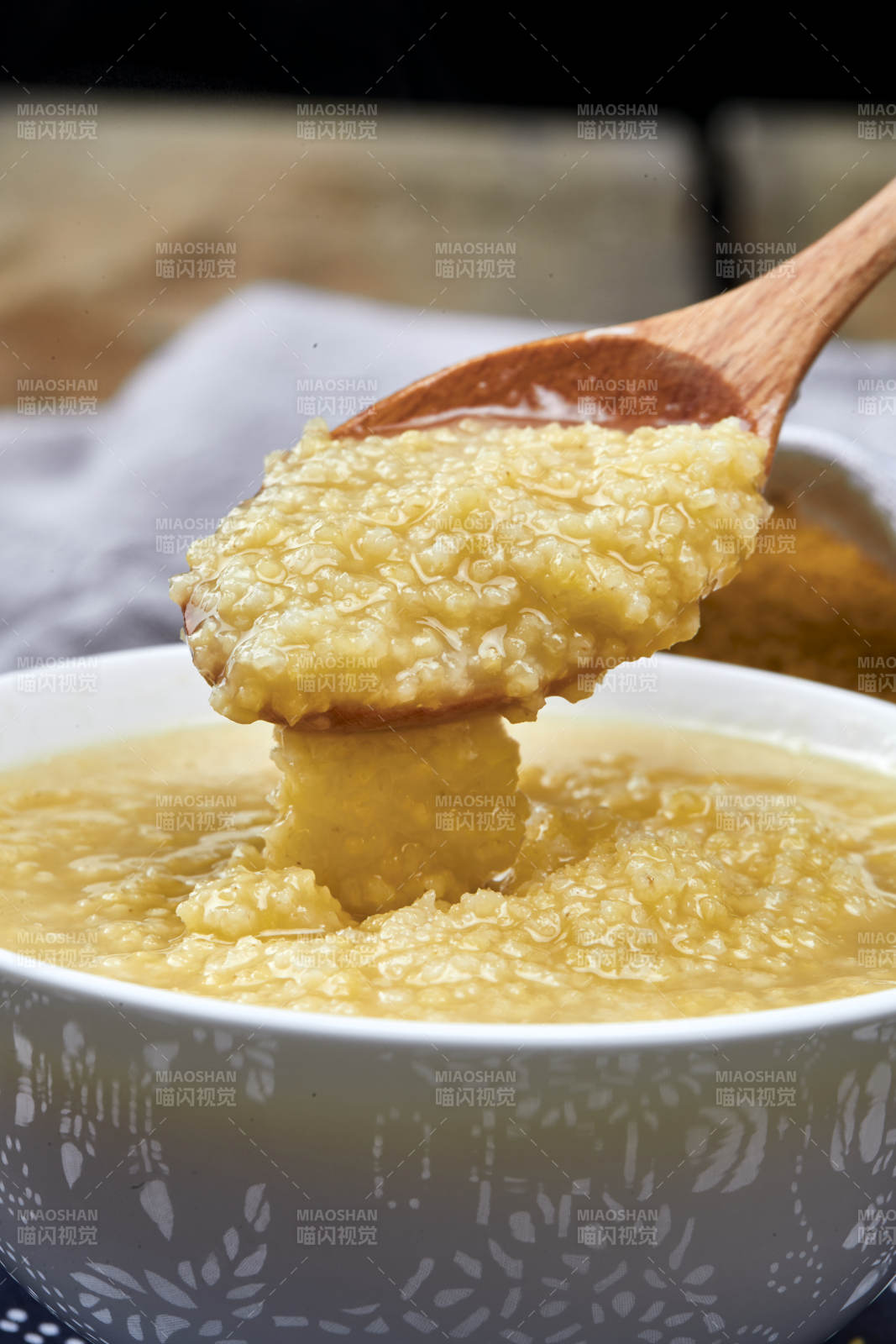 手持木勺㧟起的美味香浓小米粥图片