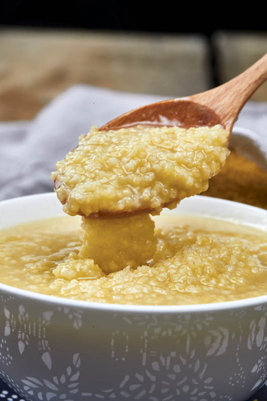 手持木勺㧟起的美味香浓小米粥图片