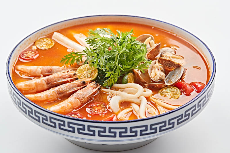 青花瓷碗装的泰式冬阴功酸辣海鲜年糕汤图片