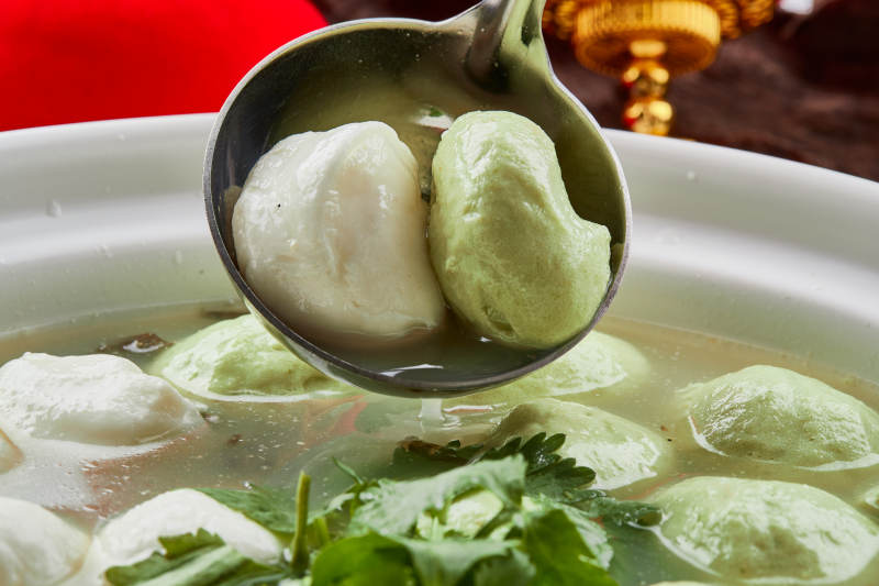 白色砂锅装的双色手打鱼丸图片