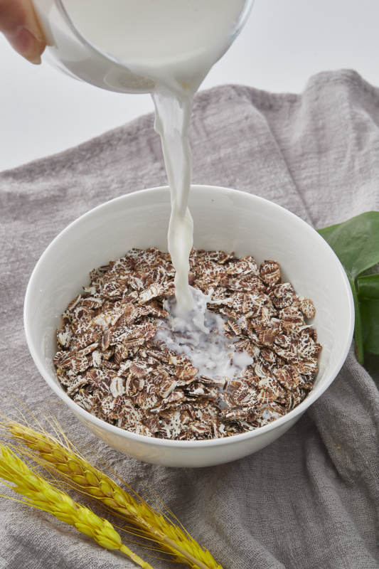 向装满低脂黑燕麦片的碗中倾倒牛奶图片