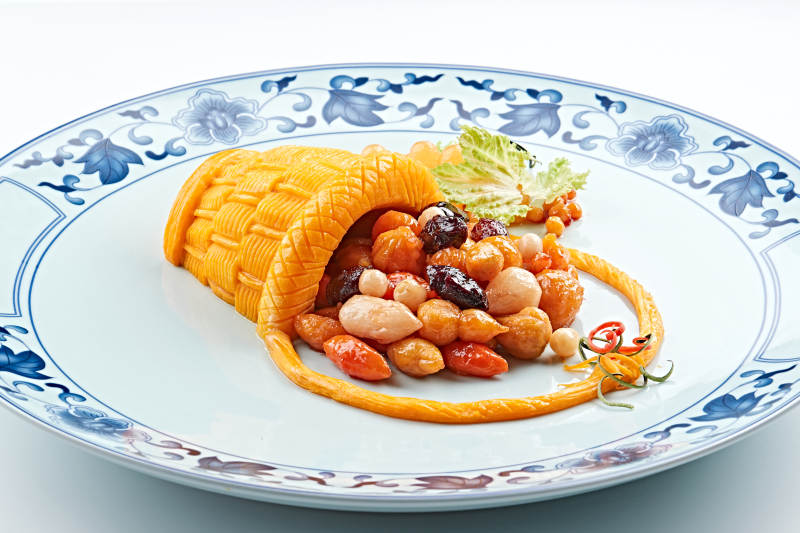 青花瓷盘装的精美雕刻摆盘的富贵花篮图片