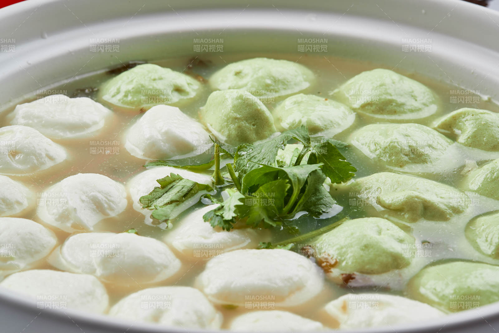 白色砂锅装的双色手打鱼丸图片