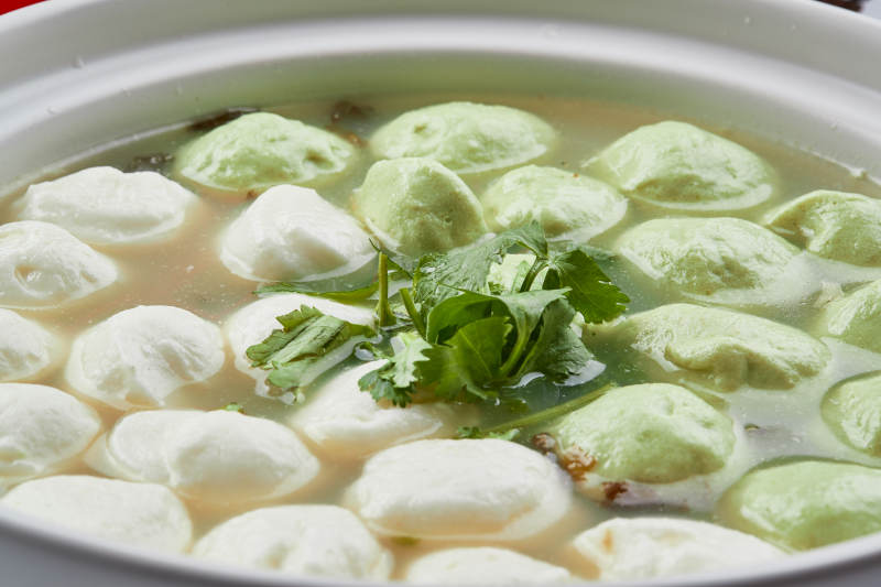 白色砂锅装的双色手打鱼丸图片