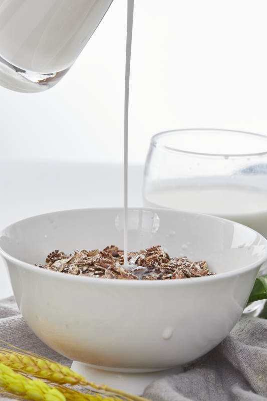 向装满低脂黑燕麦片的碗中倾倒牛奶图片