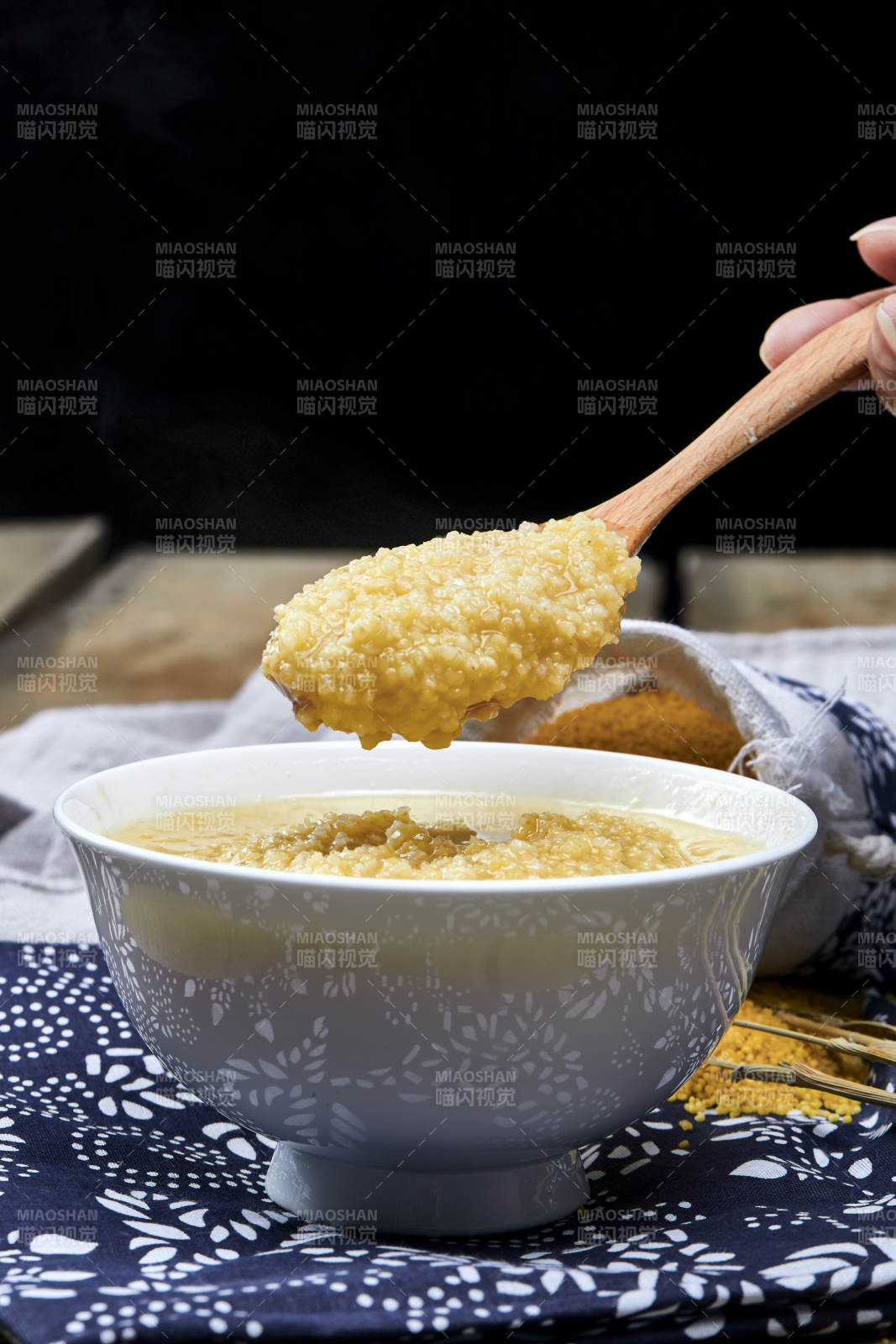 手持木勺㧟起的美味香浓小米粥图片