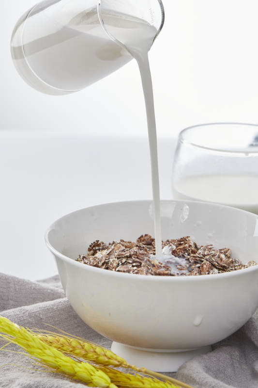 向装满低脂黑燕麦片的碗中倾倒牛奶图片