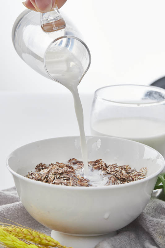 向装满低脂黑燕麦片的碗中倾倒牛奶图片