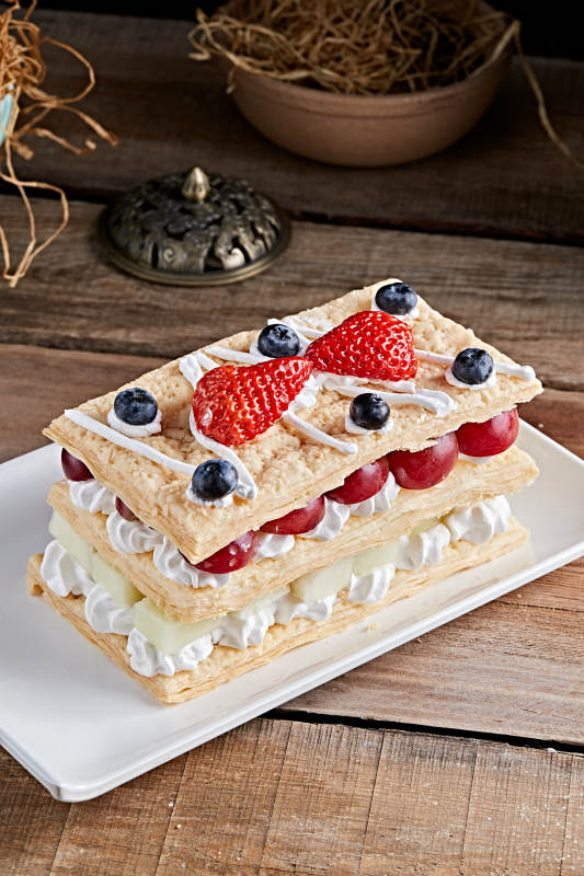 白色瓷盘装的水果戚风奶油拿破仑蛋糕图片