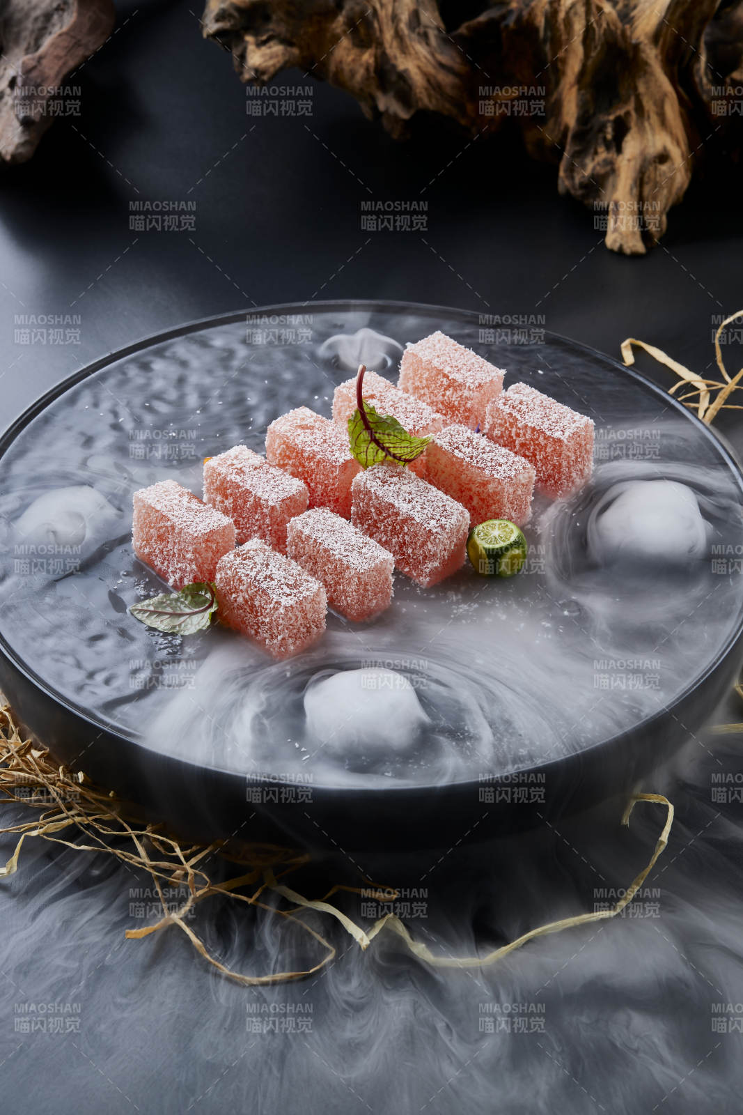 干冰缭绕的黑瓷餐具摆放的番茄糖霜江米糕图片