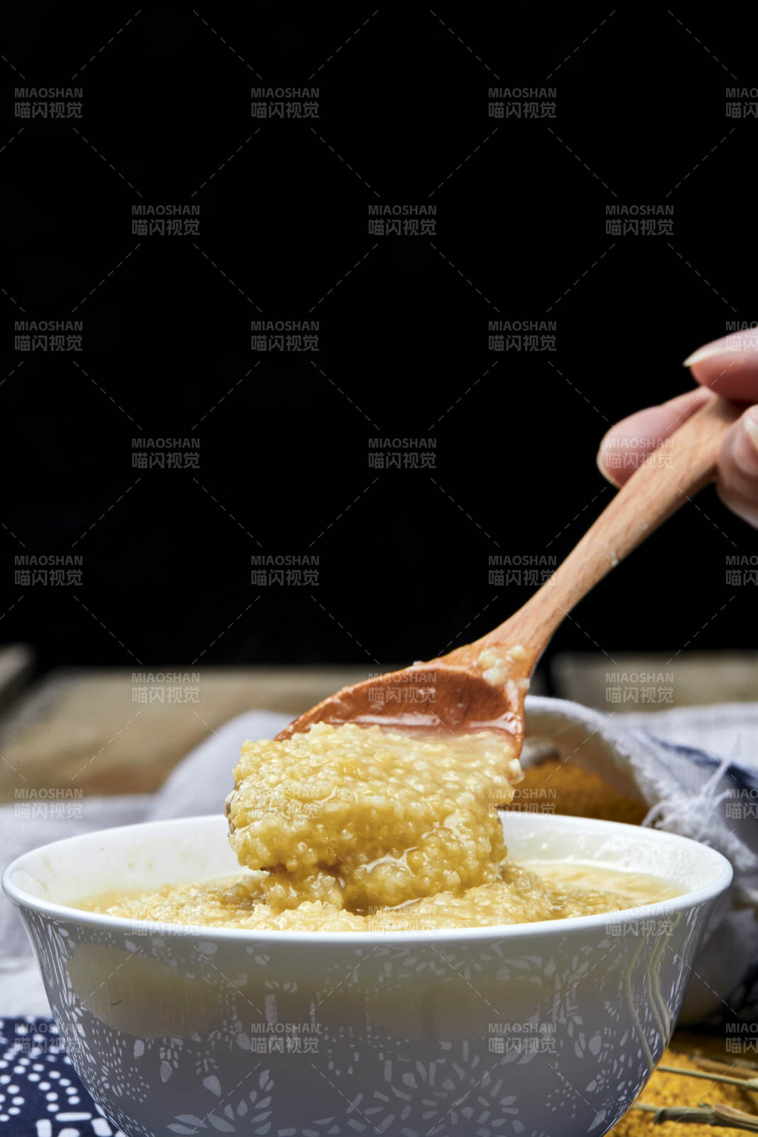 手持木勺㧟起的美味香浓小米粥图片