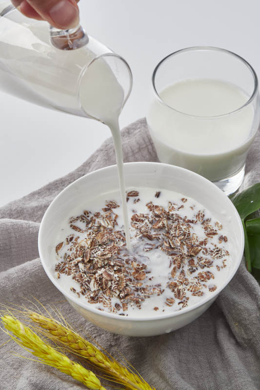 向装满低脂黑燕麦片的碗中倾倒牛奶图片