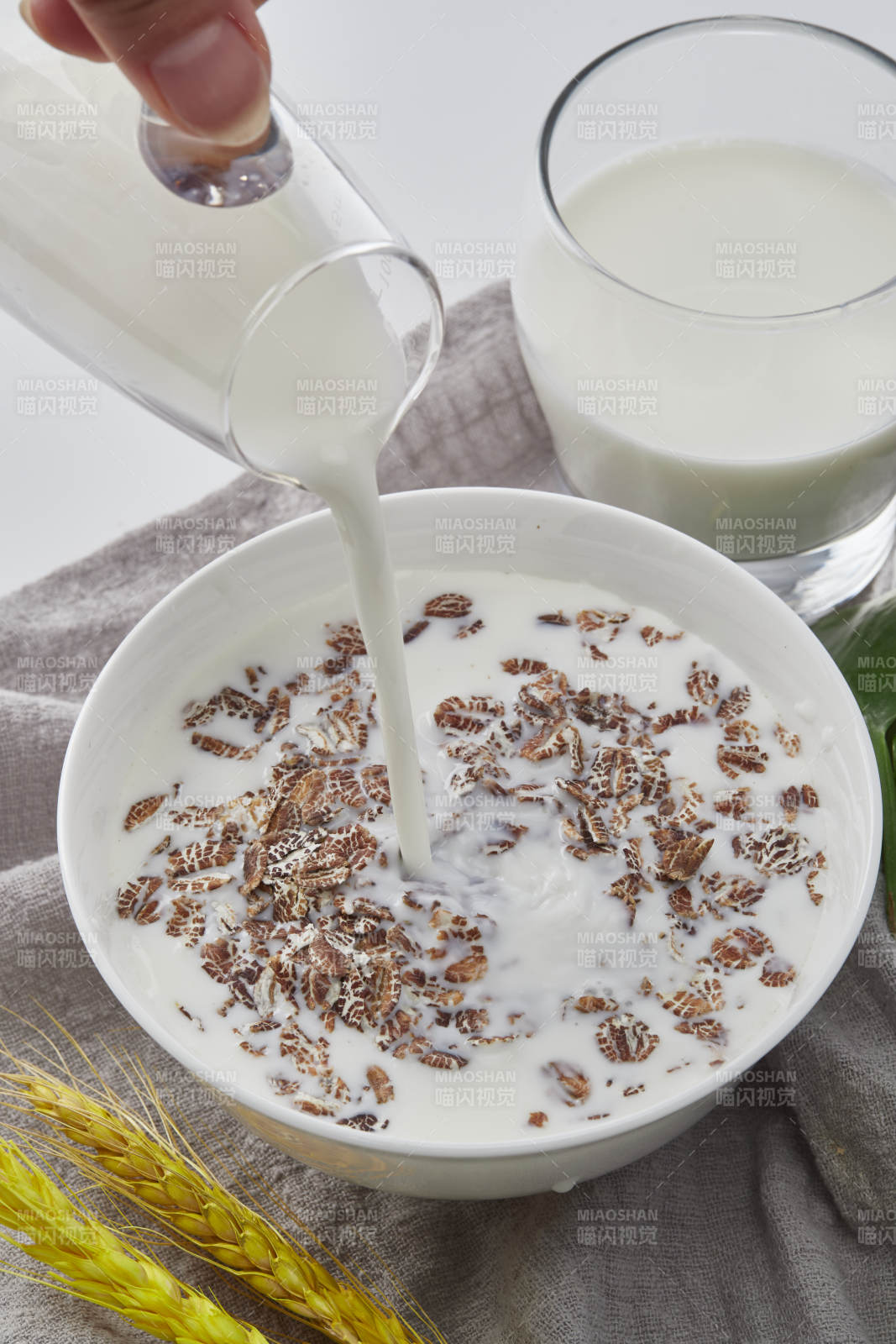 向装满低脂黑燕麦片的碗中倾倒牛奶图片