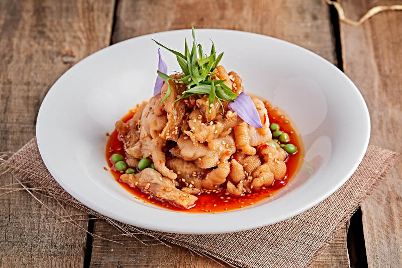 白色瓷盘装的红油酸辣脱骨凤爪图片