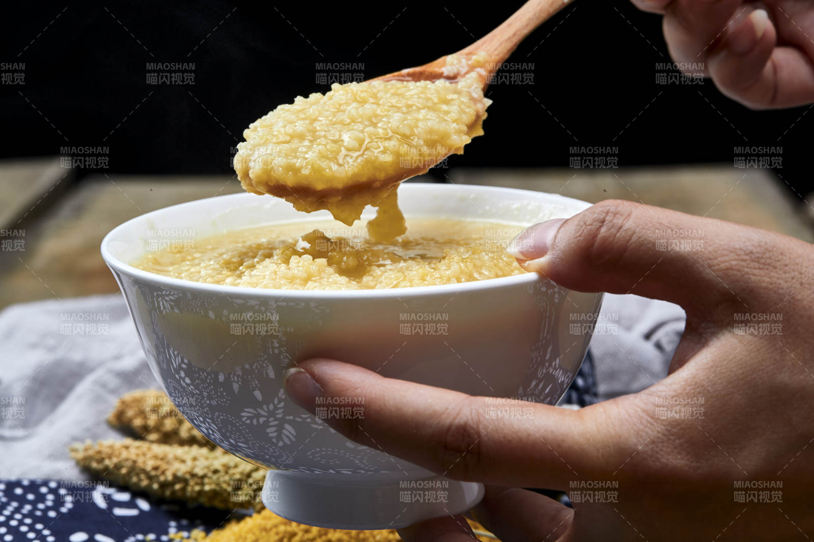 手持木勺㧟起的美味香浓小米粥图片